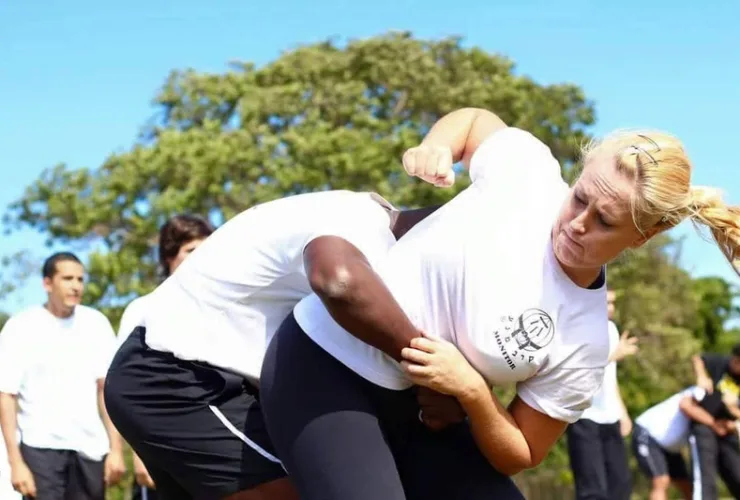 Mulher treinando Krav Maga com instrutor, praticando técnica de defesa pessoal