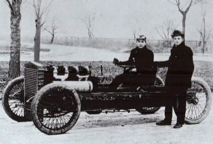Henry Ford posando ao lado de um carro de corrida no início do século XX, simbolizando o começo da Ford no automobilismo