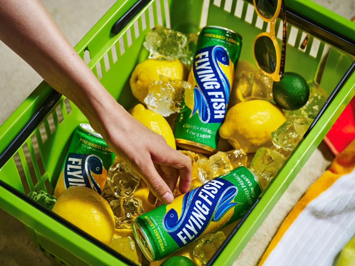 Garrafas e latas da cerveja Flying Fish mostrando embalagem com rótulo azul-claro e destaque para “limão” e “baixo amargor”.