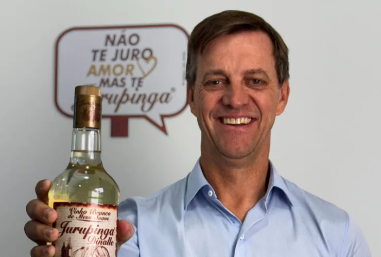 Garrafas de Jurupinga em destaque ao lado do logotipo da Zanlorenzi Bebidas, simbolizando a nova aquisição.