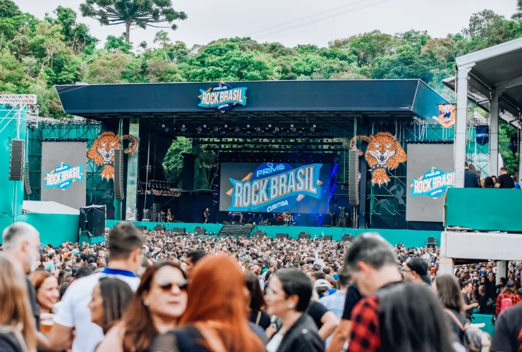 Palco da Pedreira Paulo Leminski lotado em show de rock; cartaz do Prime Rock Brasil 2025 reunindo grandes nomes do rock nacional.