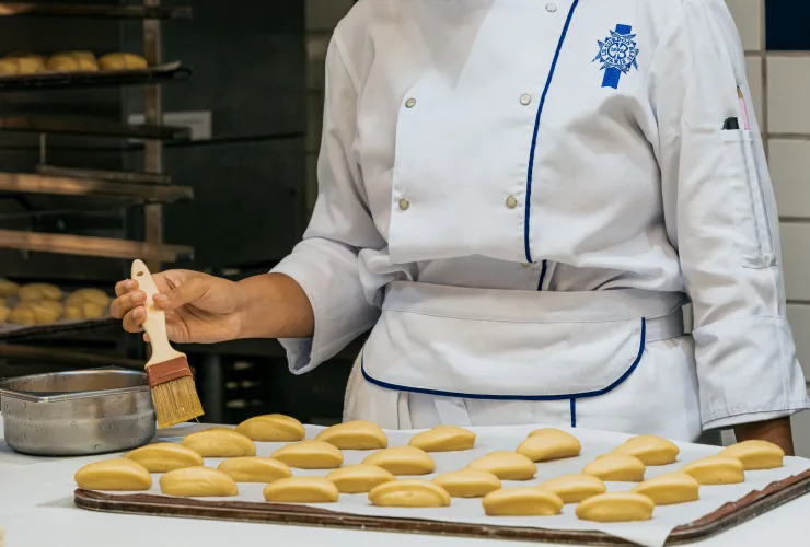 Pães artesanais dourados e viennoiseries em bancada de confeitaria profissional