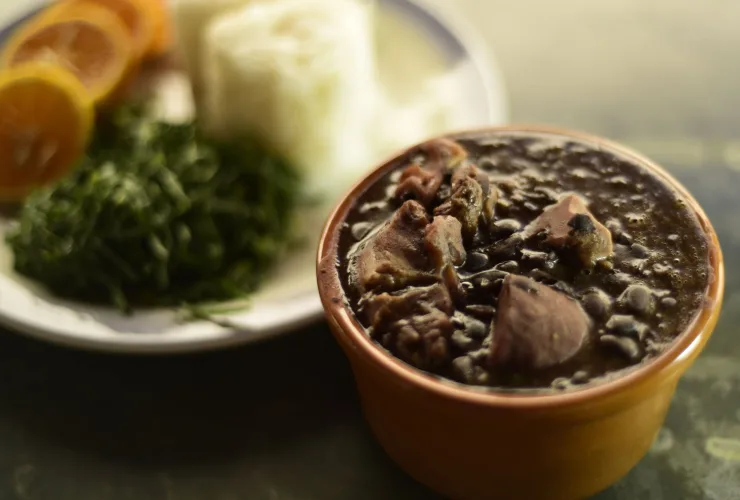 Feijoada servida em panelas de barro com acompanhamentos tradicionais na mesa