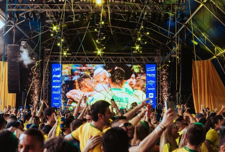 Festival Ginga em Curitiba com palco de shows e público assistindo transmissões da Copa do Mundo