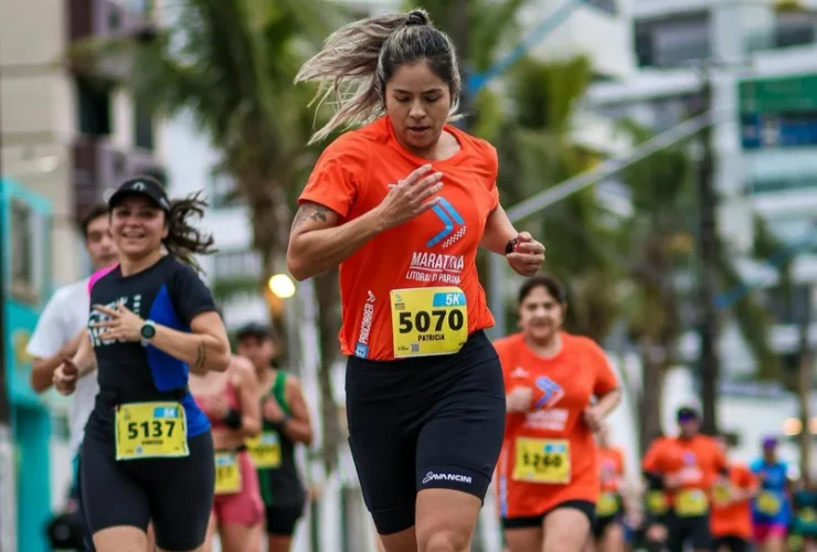 Mulheres correndo em prova de rua com cenário urbano e clima esportivo
