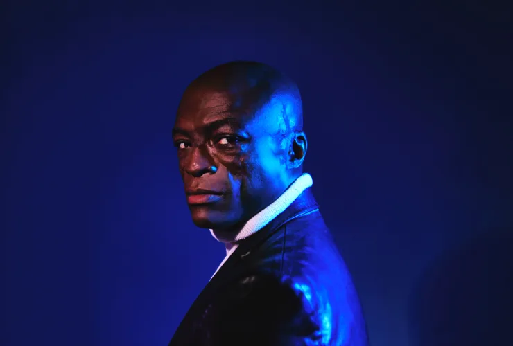 Retrato do cantor Seal sob iluminação azul em fundo escuro