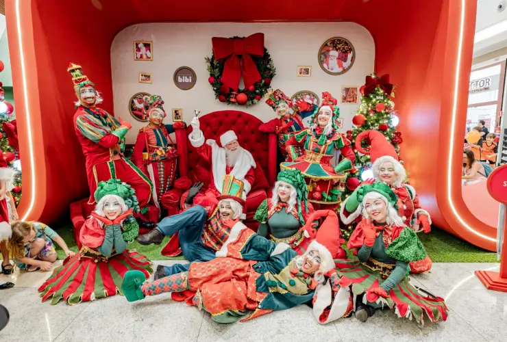 Papai Noel e personagens natalinos em cenário de Natal no shopping.