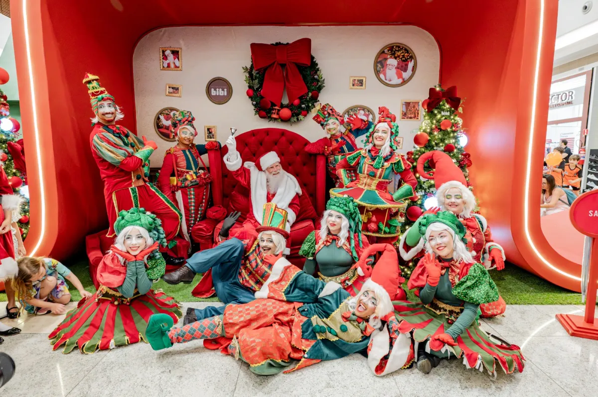 Papai Noel e personagens natalinos em cenário de Natal no shopping.