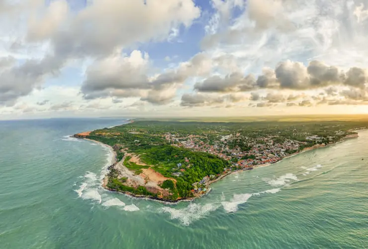 Vista aérea de faixa litorânea com praias, vegetação e construções à beira-mar