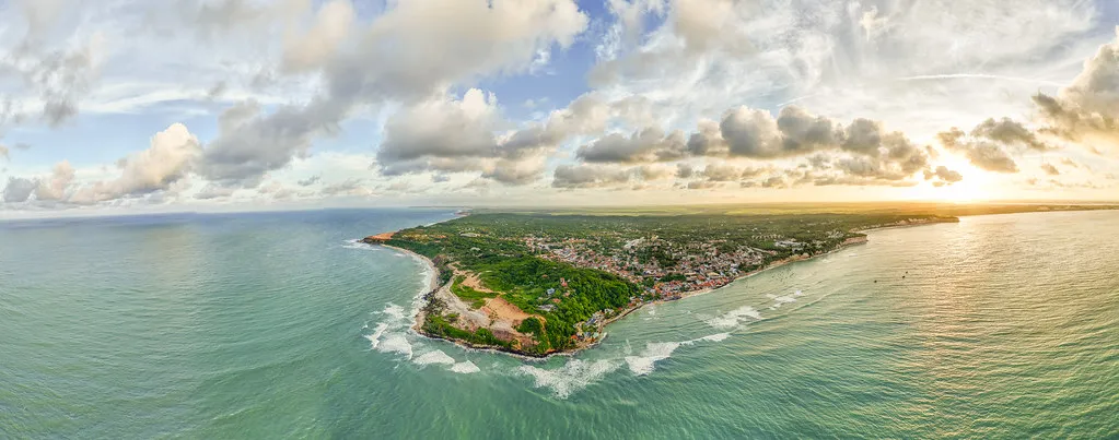 Vista aérea de faixa litorânea com praias, vegetação e construções à beira-mar