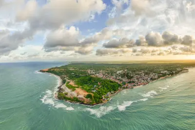 Vista aérea de faixa litorânea com praias, vegetação e construções à beira-mar