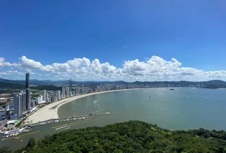 Vista panorâmica da Praia Central de Balneário Camboriú, com faixa de areia, mar e edifícios à beira-mar.