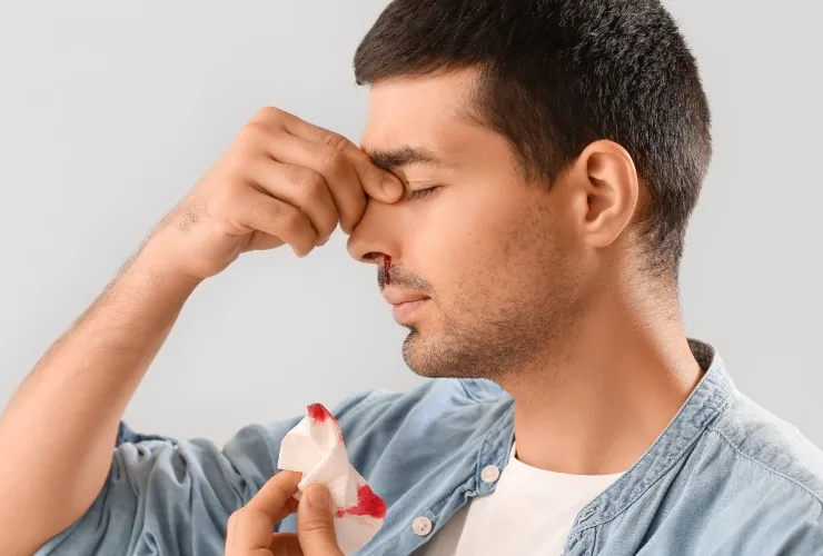 Homem de perfil, de olhos fechados, pressiona a parte de cima do nariz com os dedos