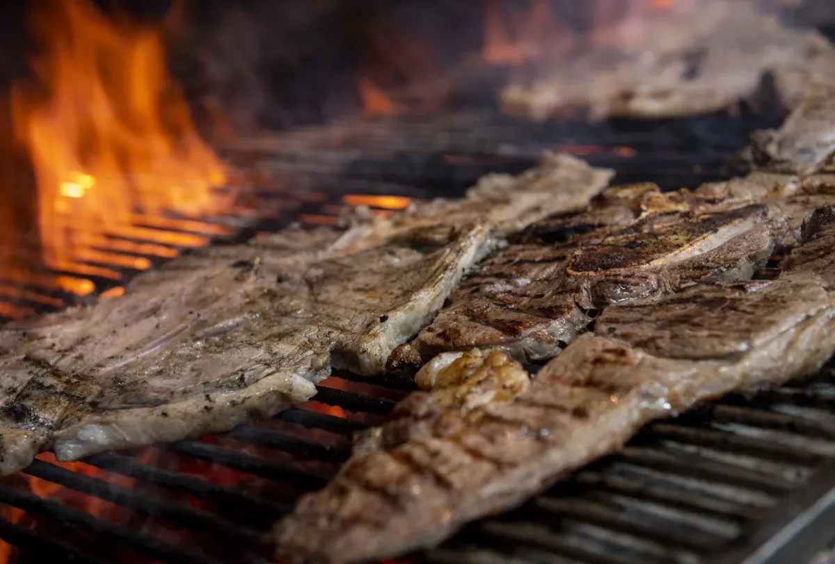 Churrasco com carnes grelhando na brasa com fogo ao fundo