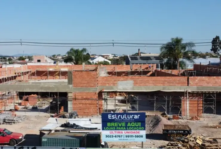Construção de imóvel comercial em andamento com placa de locação da Estruturar Imóveis Comerciais.