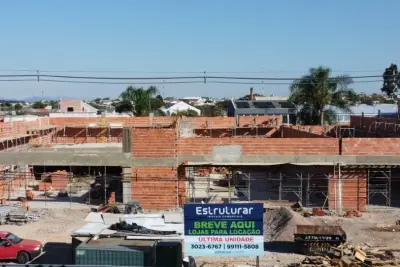 Construção de imóvel comercial em andamento com placa de locação da Estruturar Imóveis Comerciais.